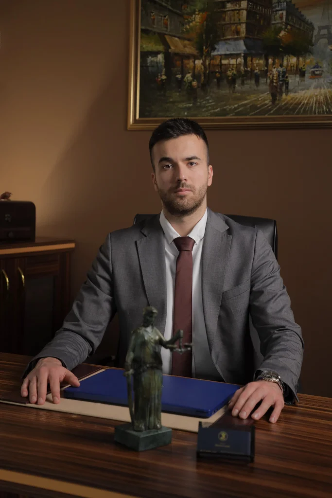 Advokat Željko Savić sedi za radnim stolom i pozira za slikanje.