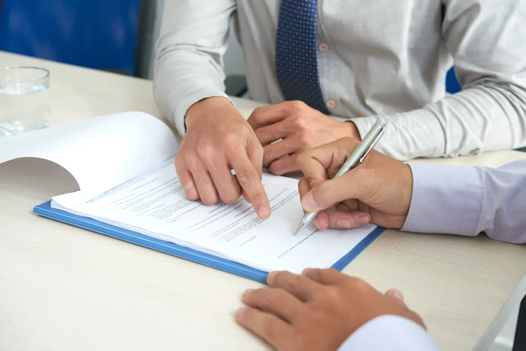 The lawyer shows his client where to sign the contract.